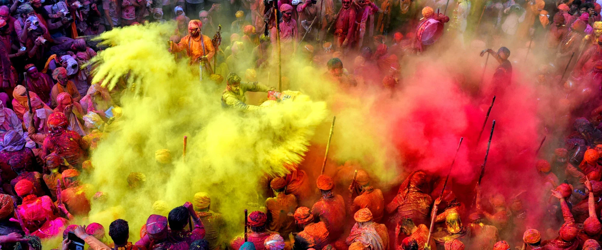 Yellow and pink powder thrown by crowds of people in celebration of Holi